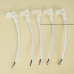 Five white connector wires with colorful ends arranged in a row on a beige background.