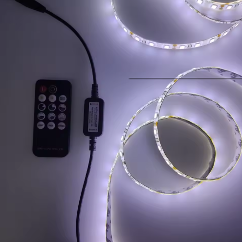 Coiled LED strip light connected to a remote control, emitting a bright white glow on a flat surface.