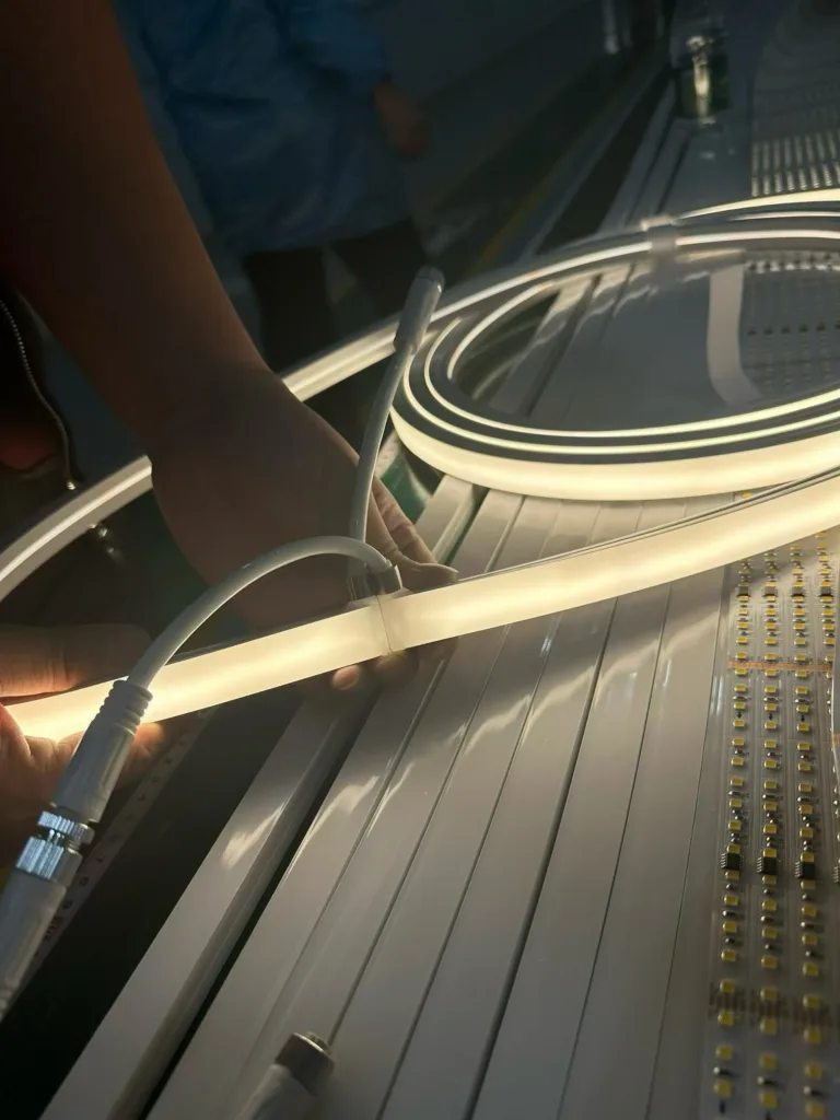 Hands inspecting silicone neon flex light strip in a workshop setting, highlighting the flexible design and light emission.