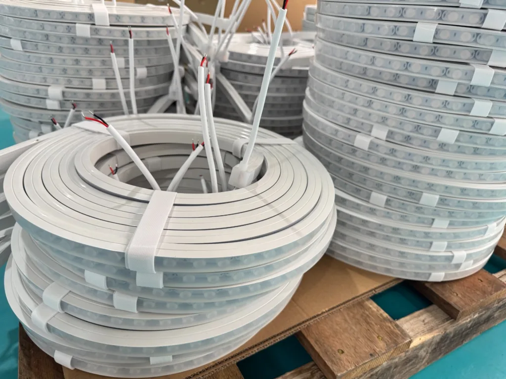 Coiled silicone neon flex lighting rolls with exposed wires, stacked on a pallet, ready for transportation.