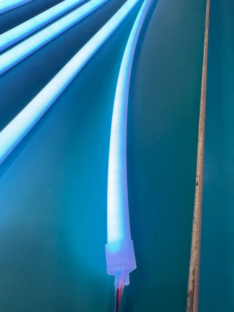 Multiple bright blue silicone neon flex LED strips arranged in curves on a smooth surface, showcasing seamless illumination.