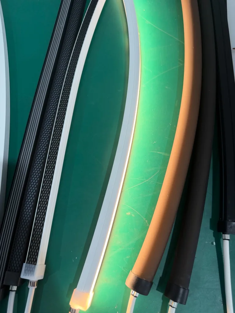 Close-up view of flexible silicone neon flex lighting with different profiles and textures, displayed on a green surface.