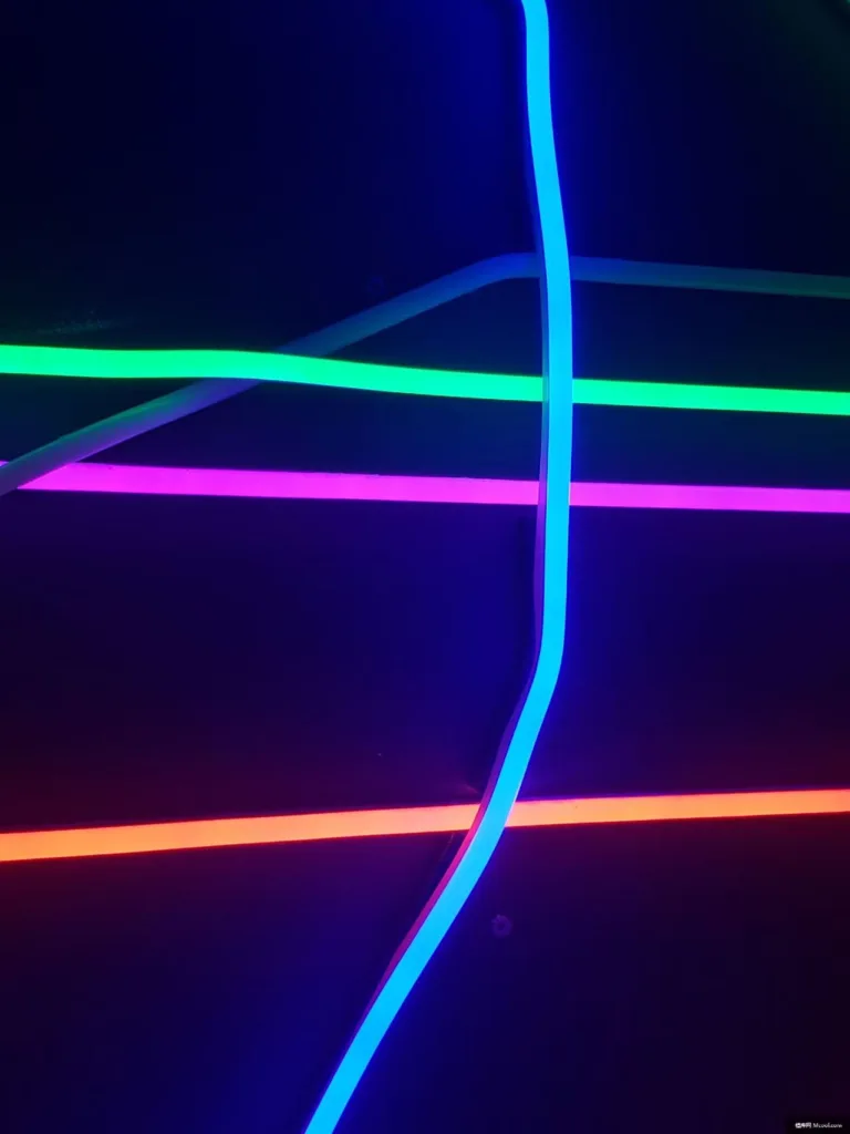 Dynamic arrangement of colorful LED neon lighting strips in blue, green, pink, and red, glowing against a dark background.