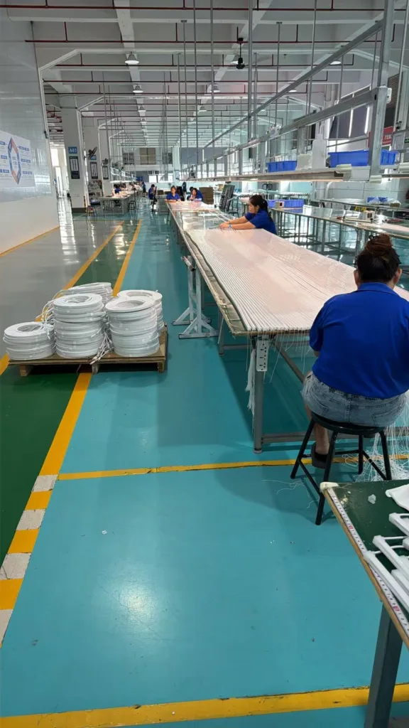 Workers assembling silicone neon lighting strips in a large, organized factory setting with clean floors and machinery.