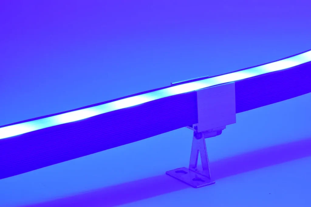 Close-up of silicone neon flex lighting strip in blue hue secured with a metal mounting bracket for installation.