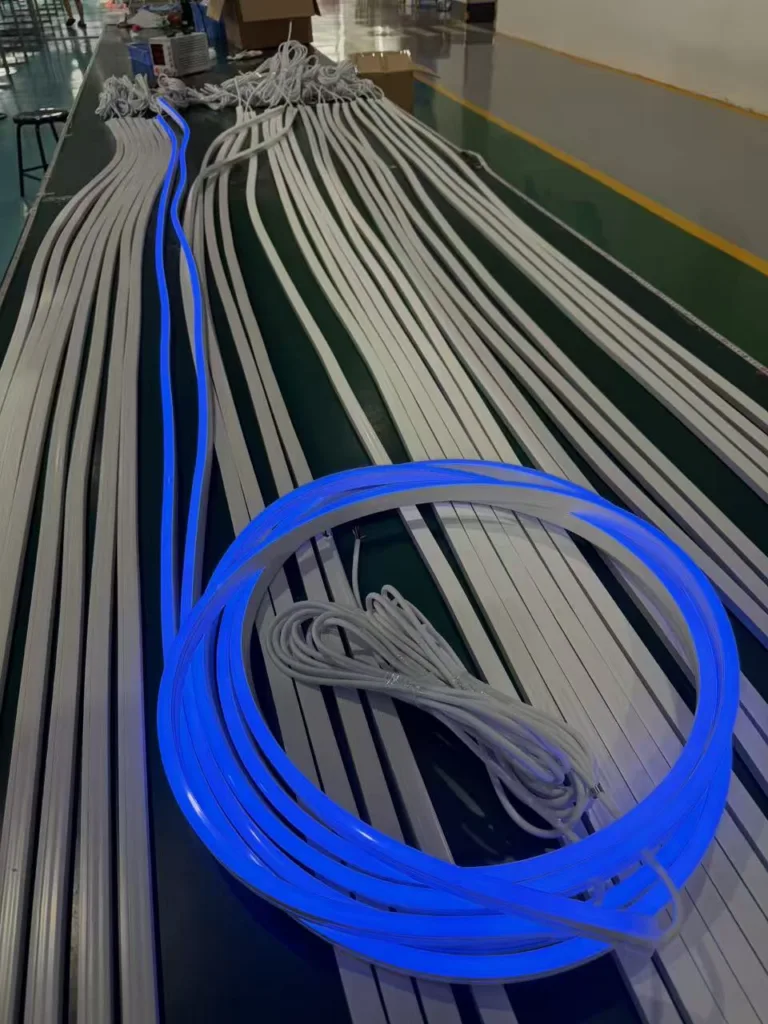 Blue silicone neon flex lights neatly arranged on a production line alongside white wiring and components in a manufacturing facility.